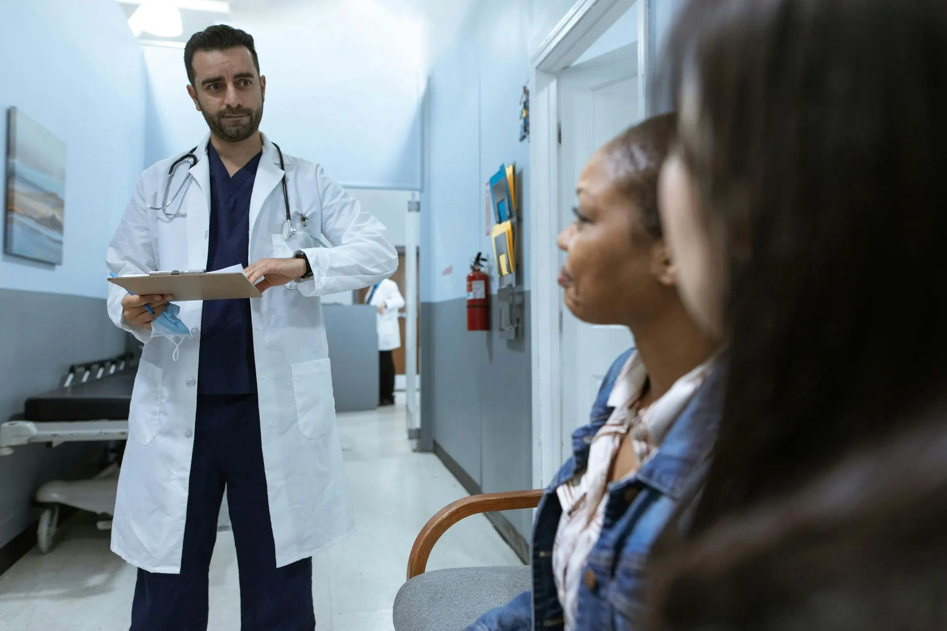 Doctor speaking with two patients in a hospital hallway